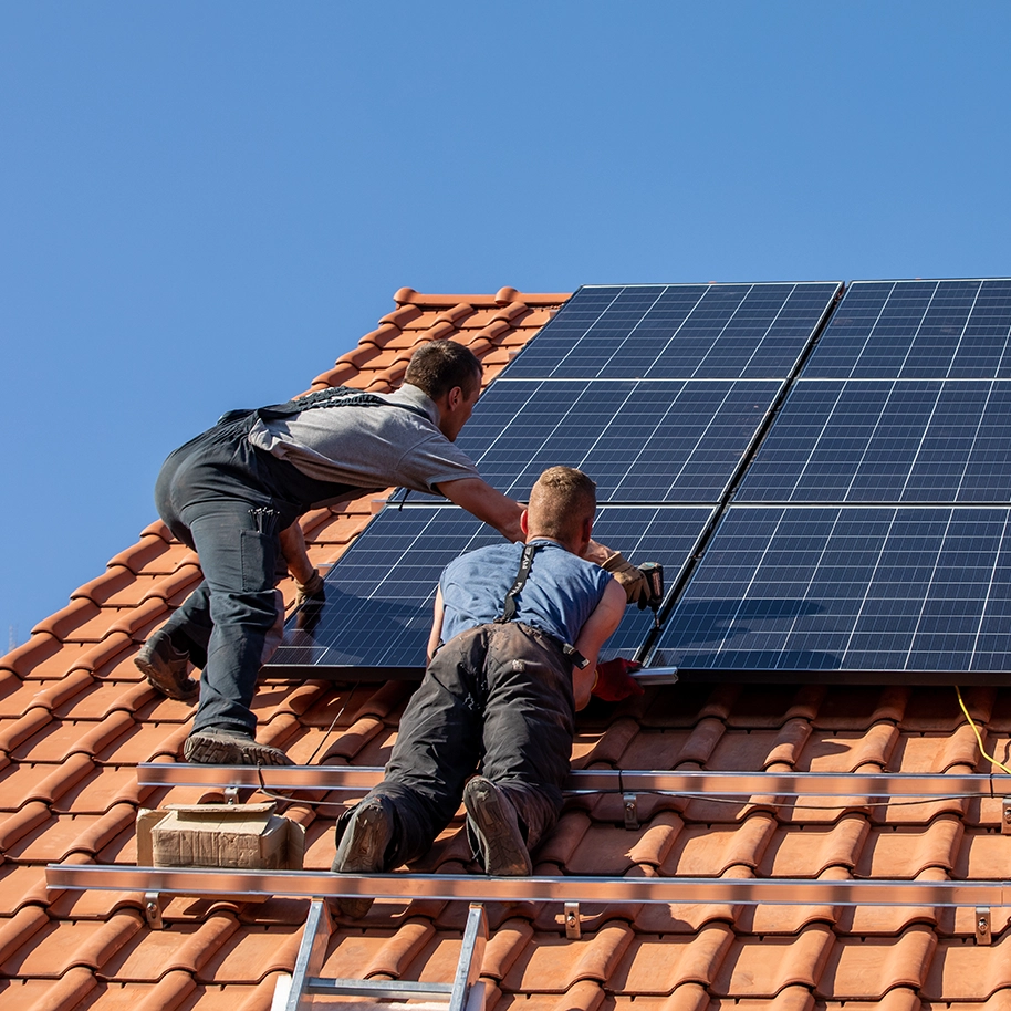 Installationsprozess einer Photovoltaik-Anlage auf einem Dach, bei dem Solarpanels fachgerecht montiert werden, um erneuerbare Energie zu erzeugen.